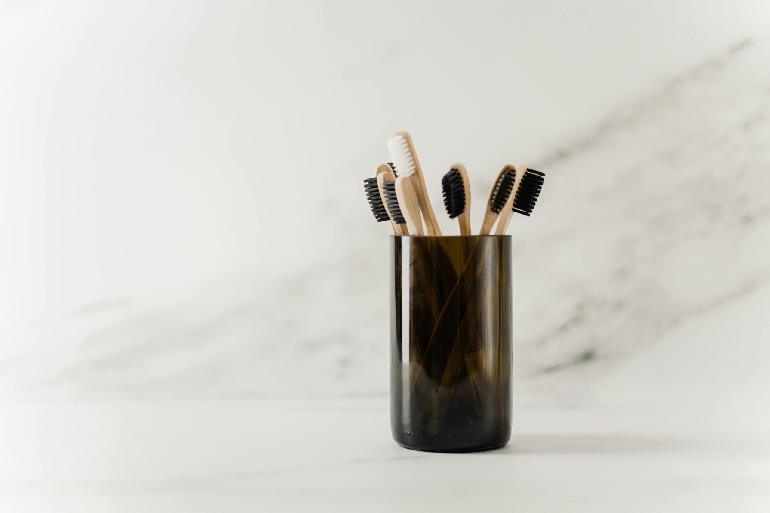 Set of eco-friendly bamboo toothbrushes in a glass holder, showcasing a minimalist design.