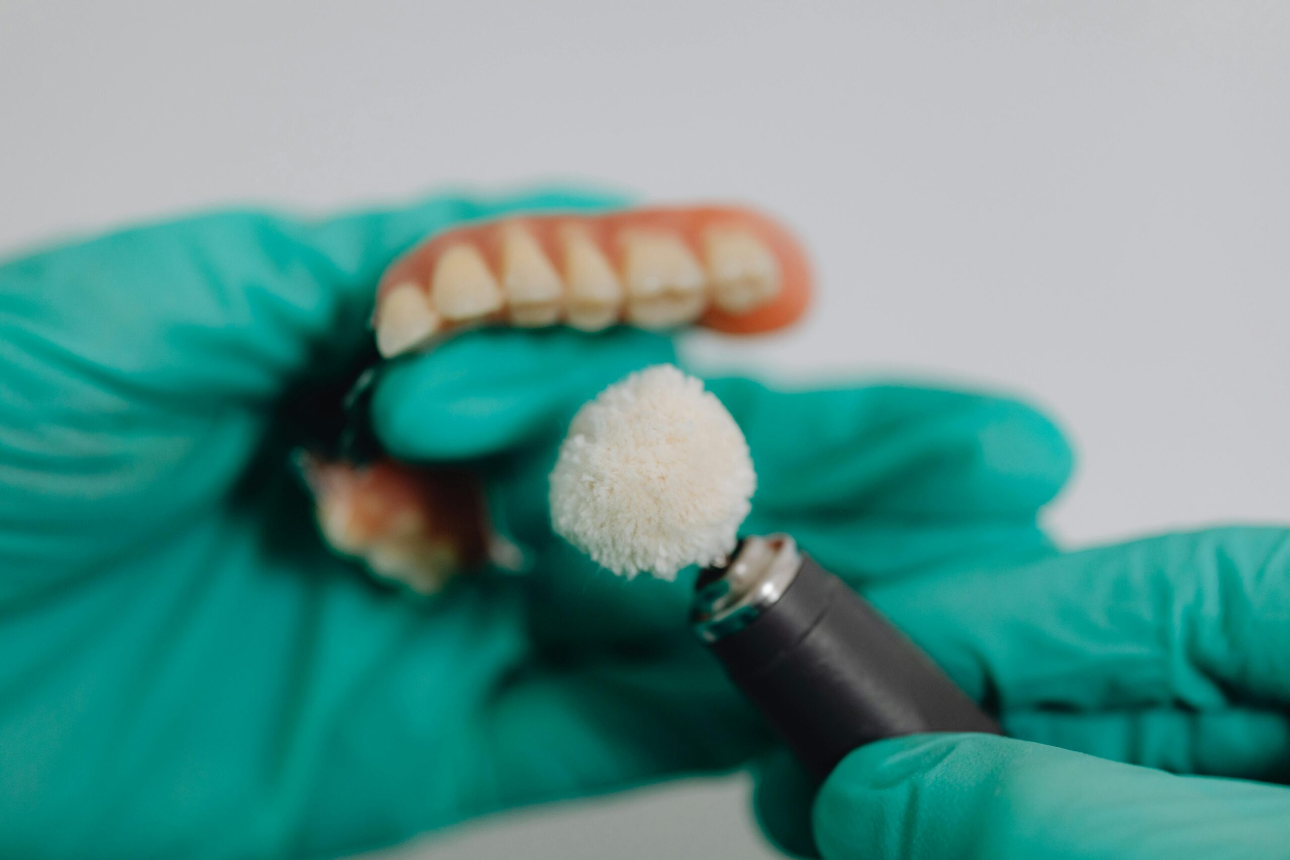 Detailed image of dentures being polished by a dental professional wearing gloves. Ideal for dental care topics.